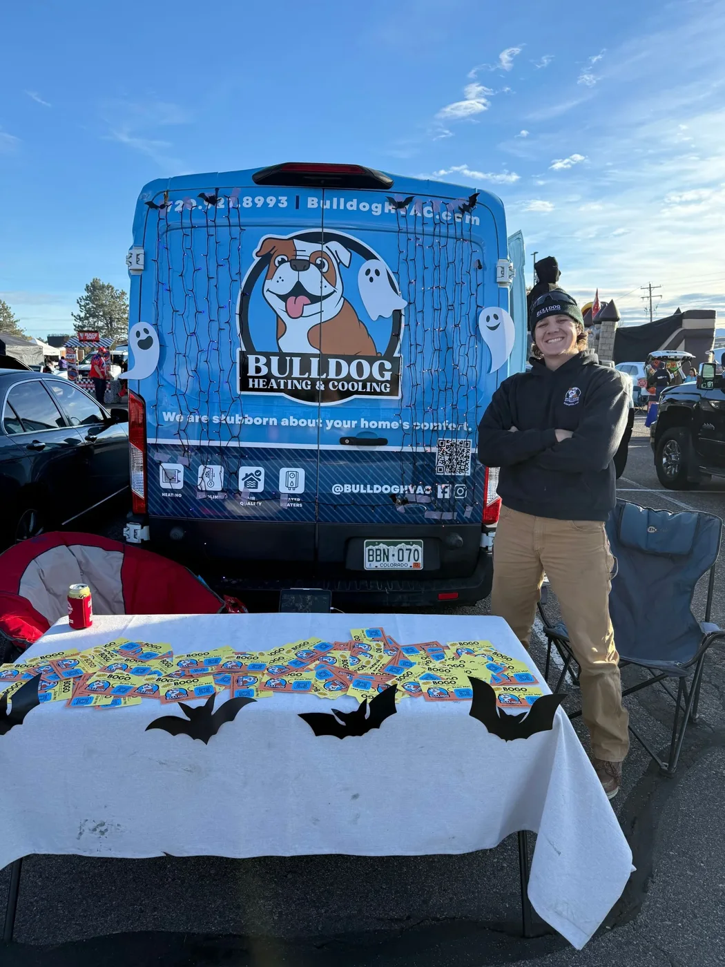 Bulldog Heating & Cooling employee at branded van during community event with promotional materials