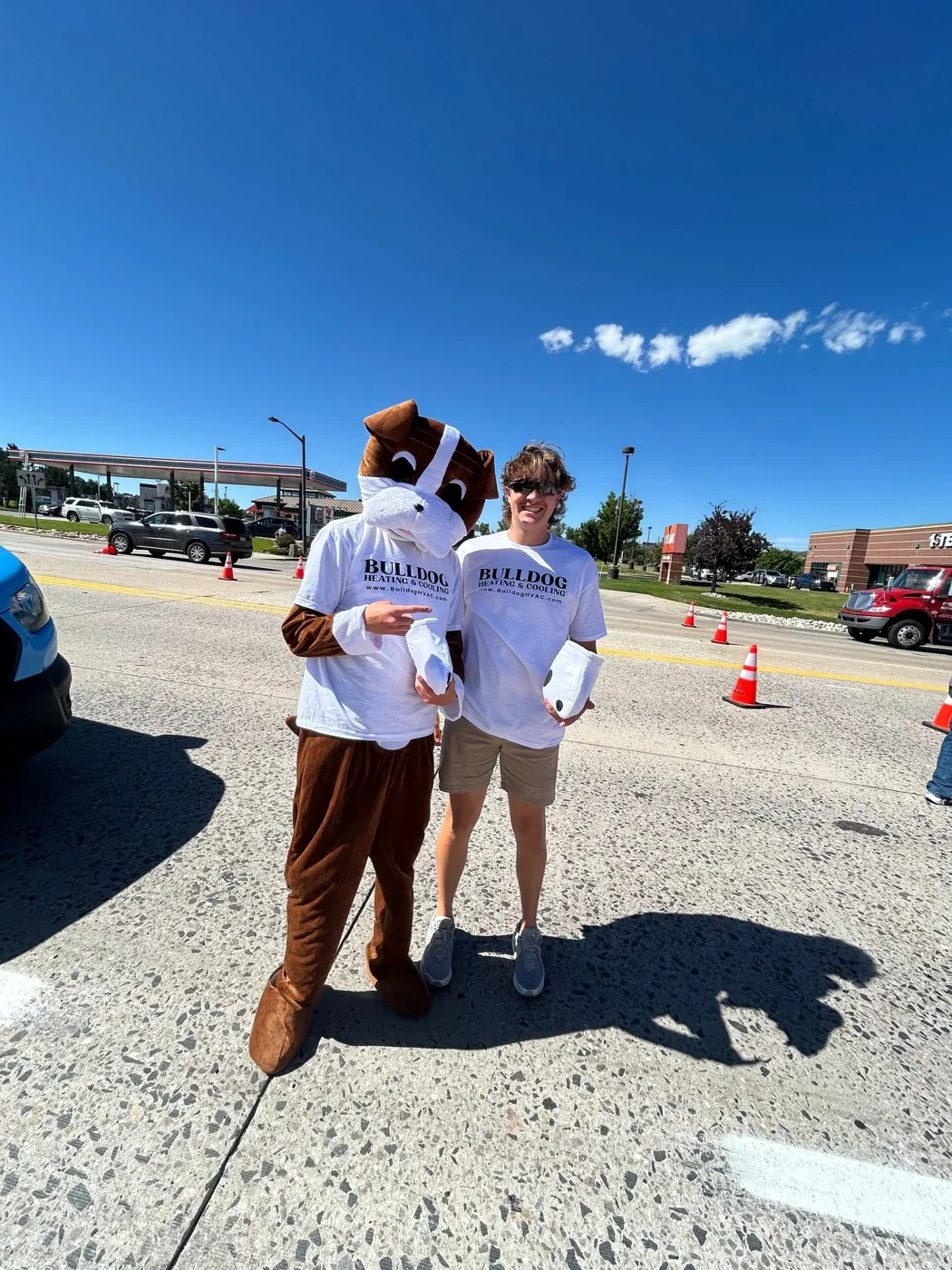 Bulldog mascot and person in white Bulldog Heating shirt at outdoor event