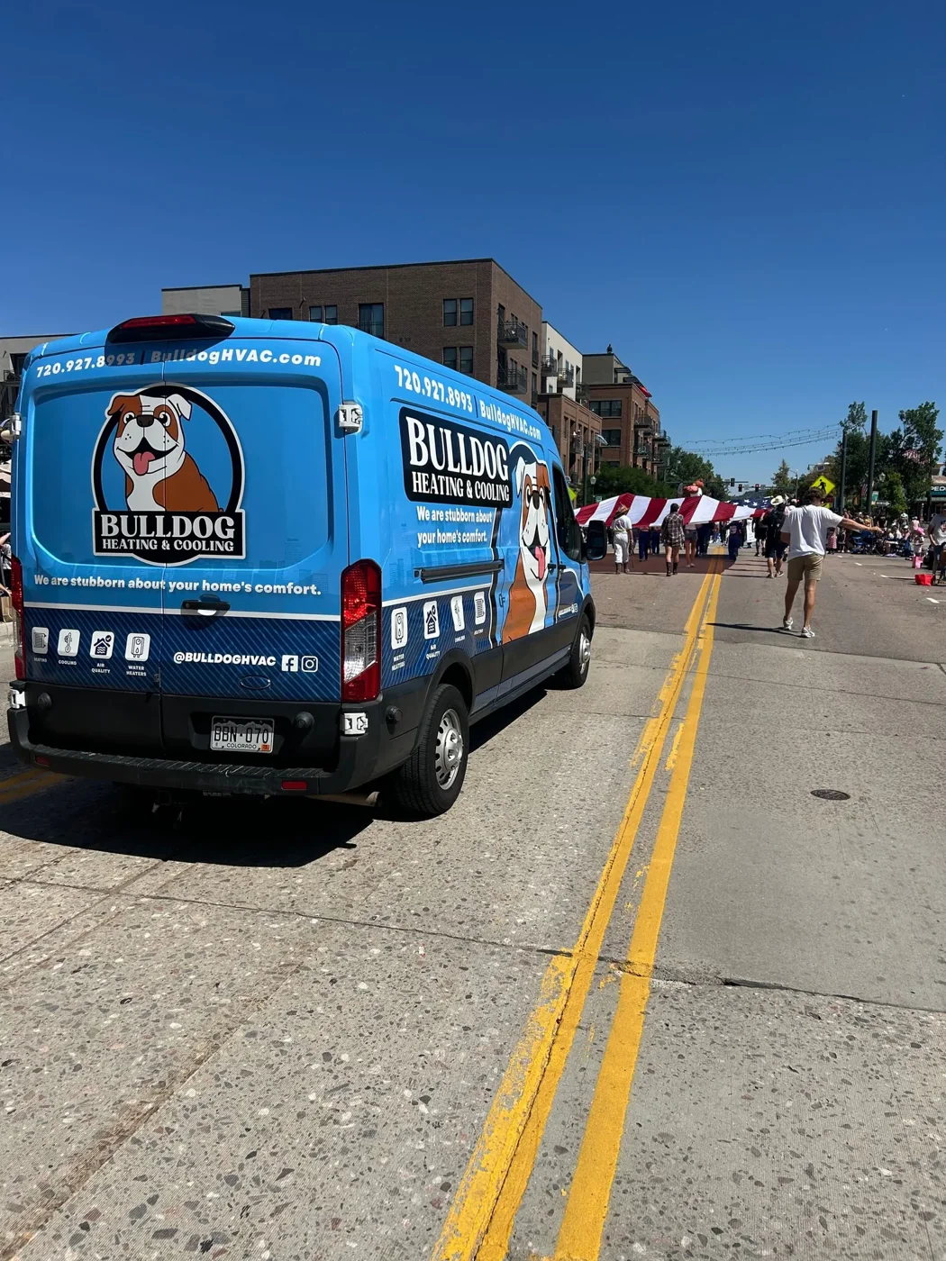 Bulldog Heating and Cooling blue service van in parade with bulldog logo and contact information visible
